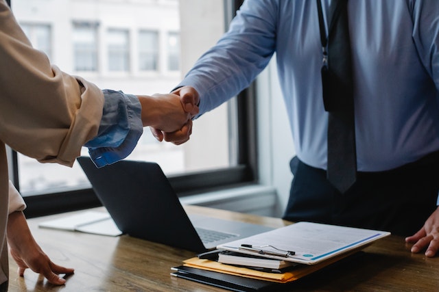 people at desk shaking hands
